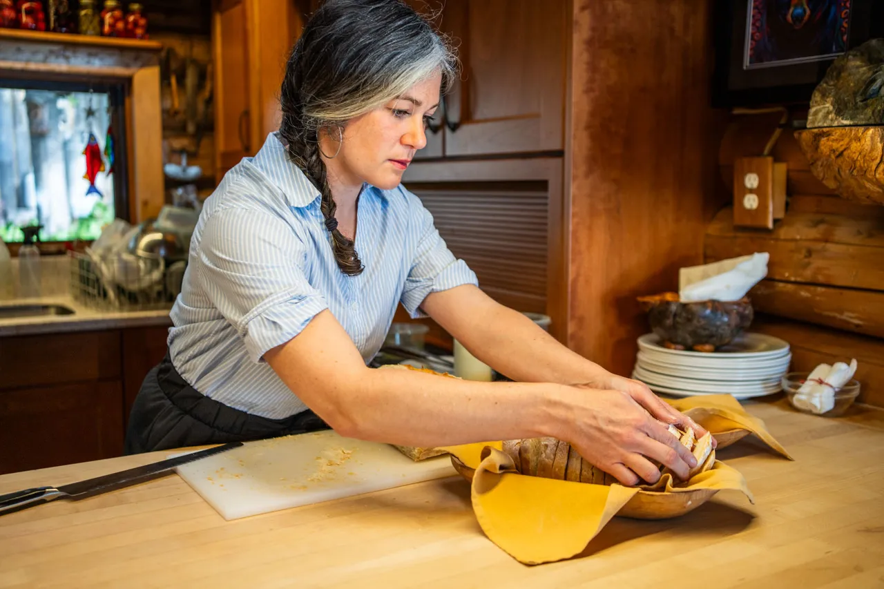 Cook working dough at a timber counter in the lodge kitchen