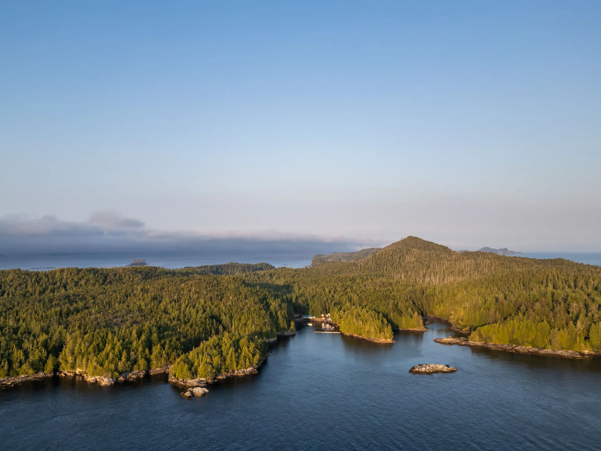 Aerial view of forested islands and calm blue channels around Hurst Island at golden hour