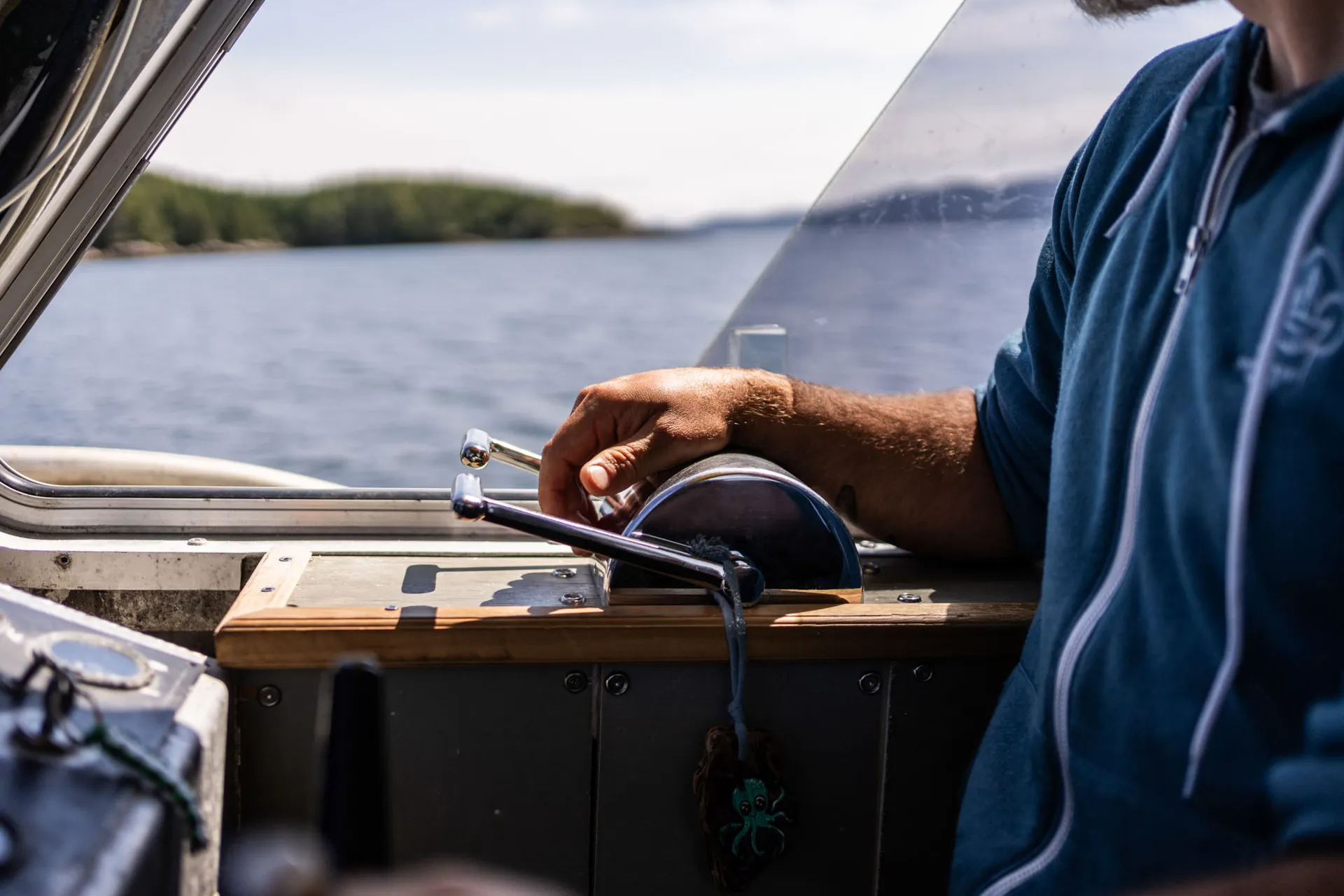 Skipper at the helm of the dive boat, hand on the throttle, the strait opening ahead