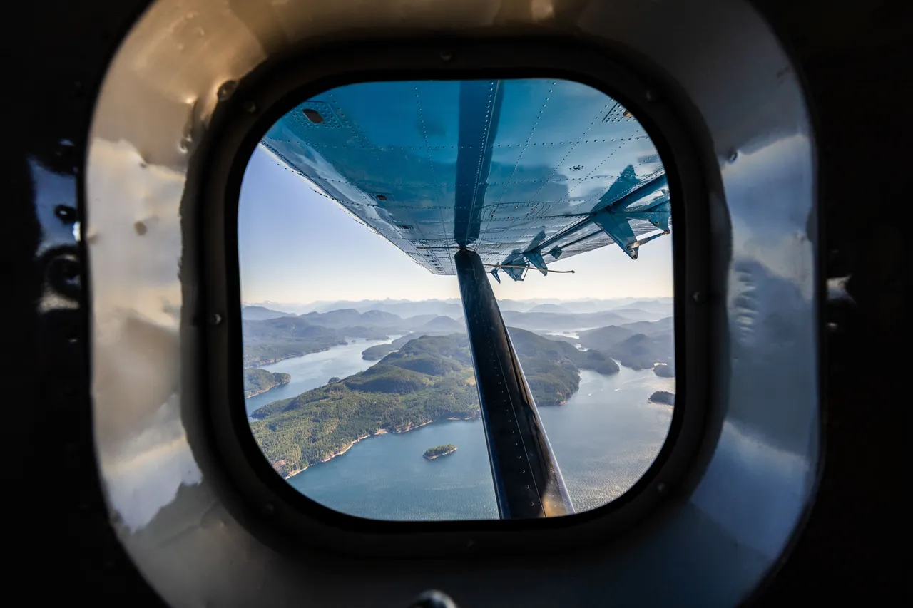 View through a floatplane window over forested islands and channels on the flight in to the lodge