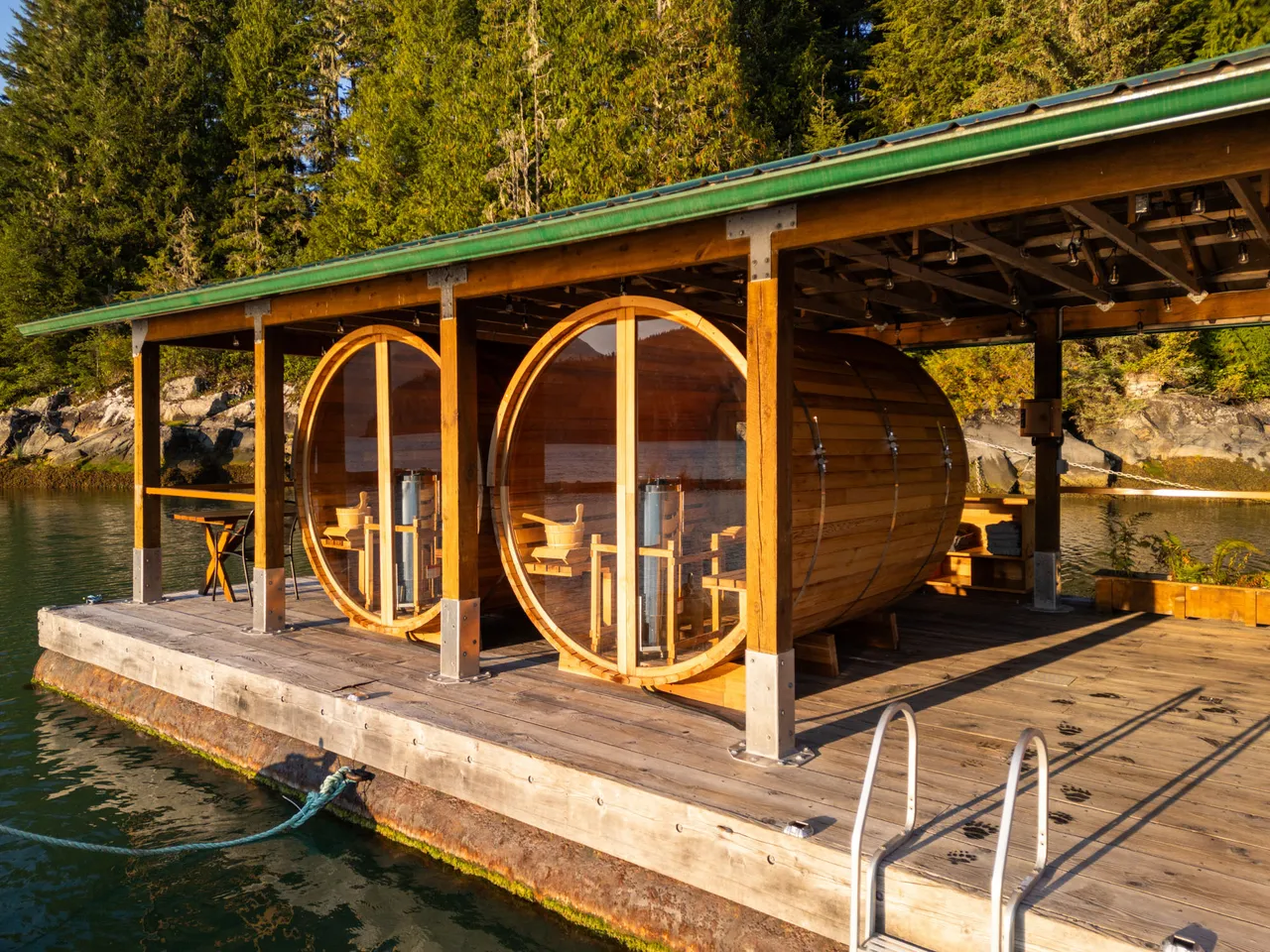 Two cedar barrel saunas with round glass doors on the lodge's floating dock, open to the water