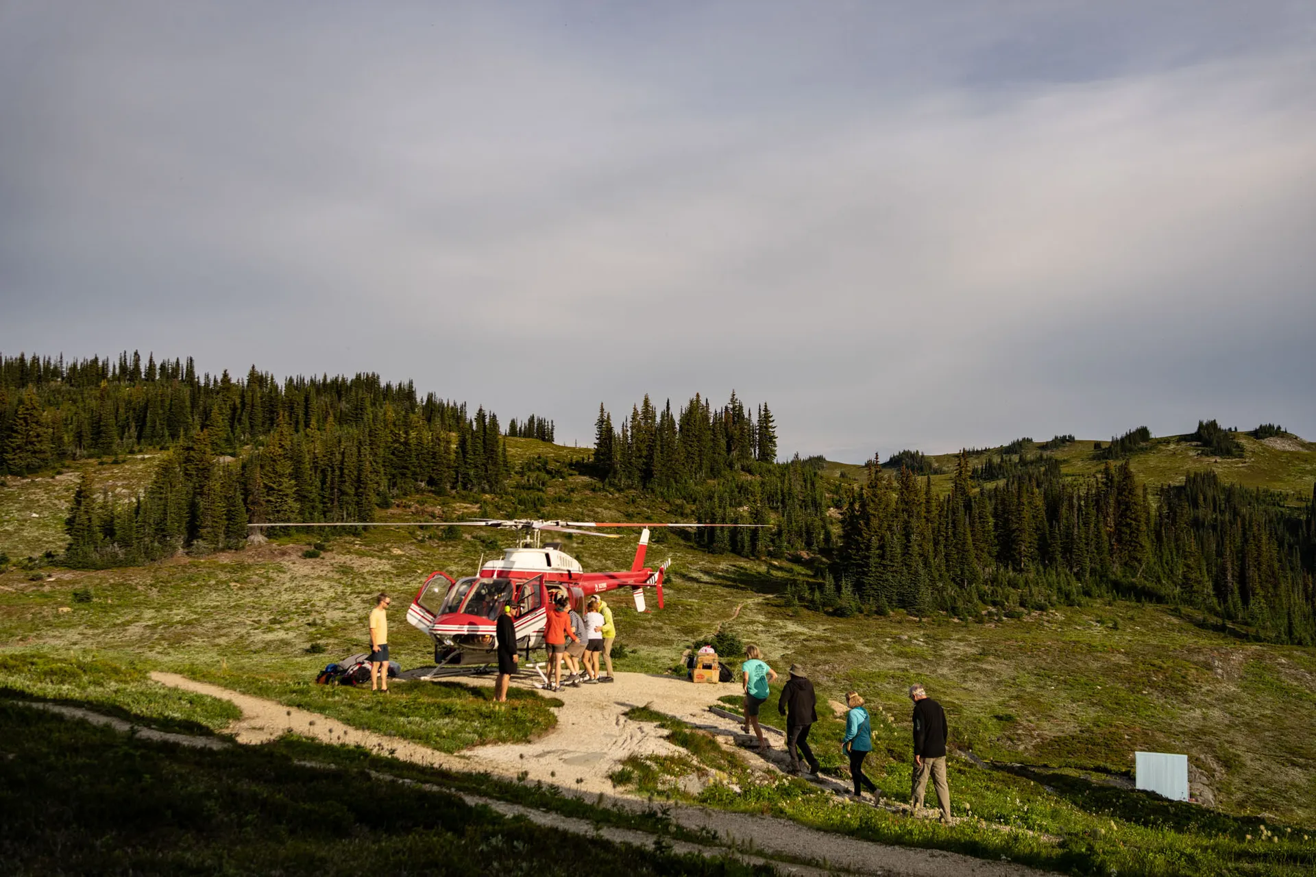 Guests unloading from a red and white helicopter on the meadow landing pad