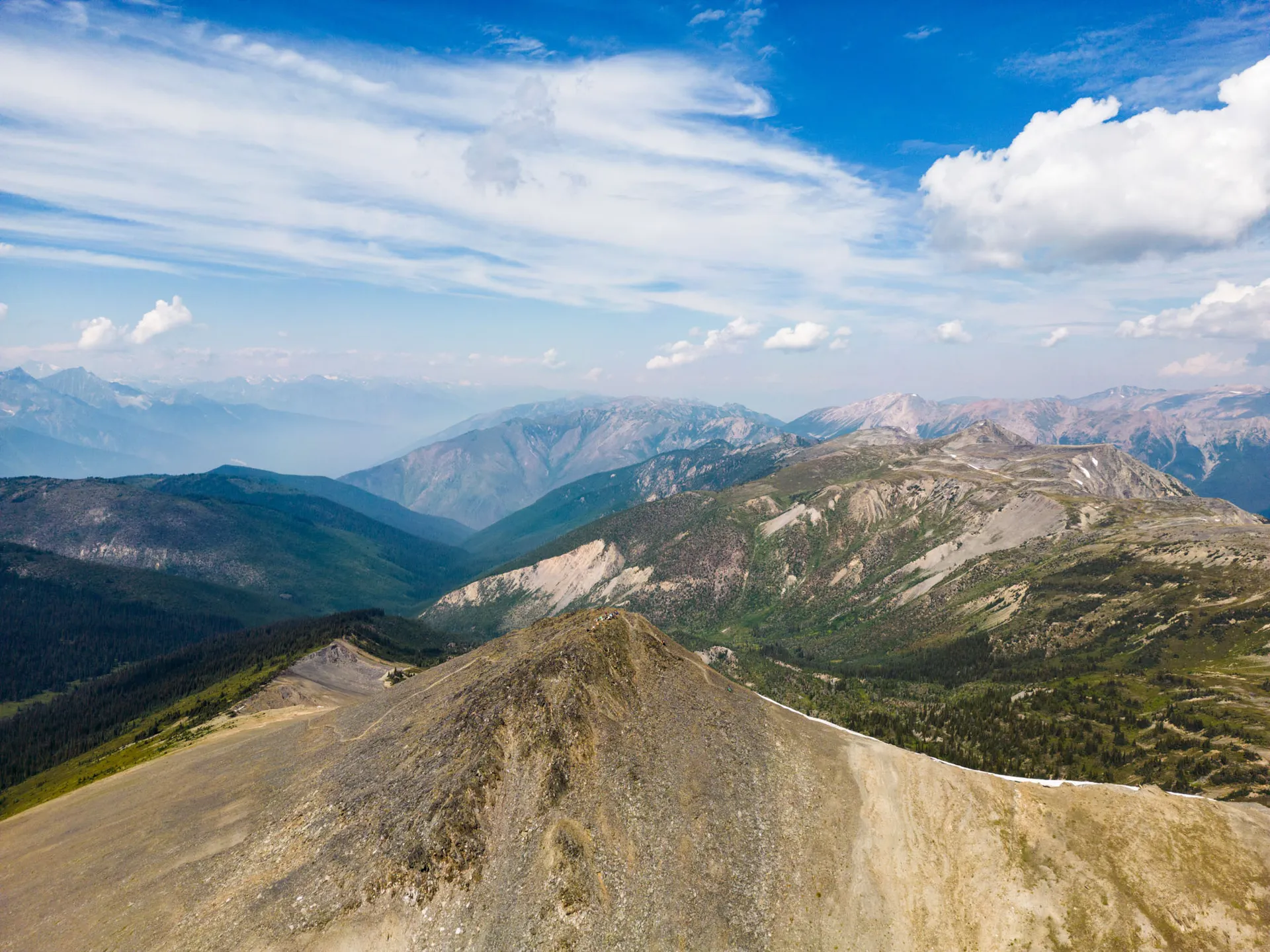 Broad scree-and-meadow ridge falling away to hazy blue ranges