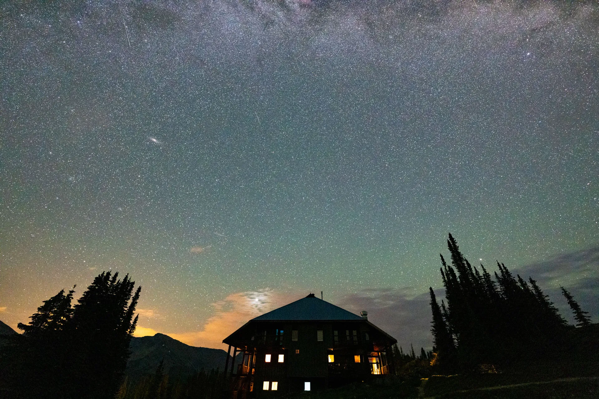 The lodge glowing under a dense star field with the Milky Way overhead