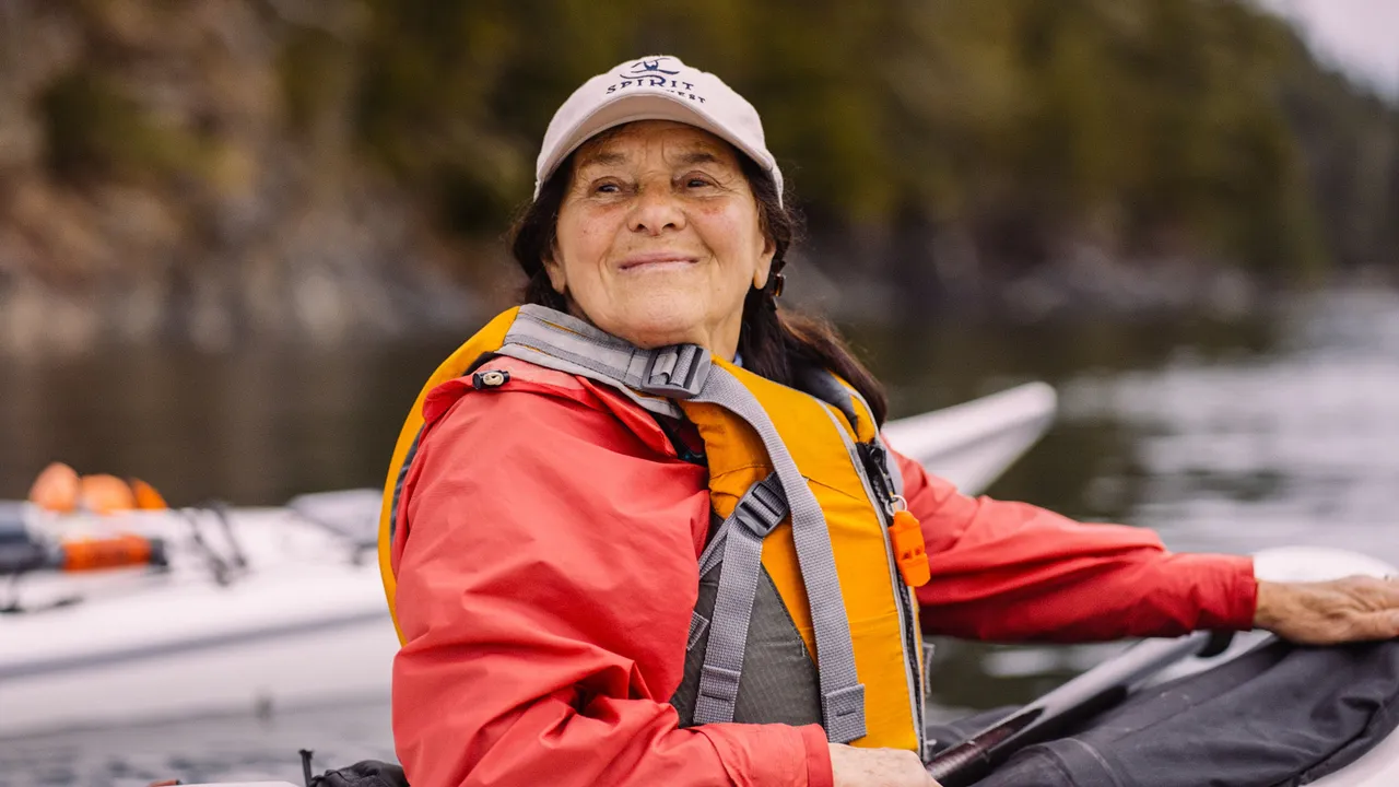 Smiling paddler in a red jacket and life vest seated in a sea kayak