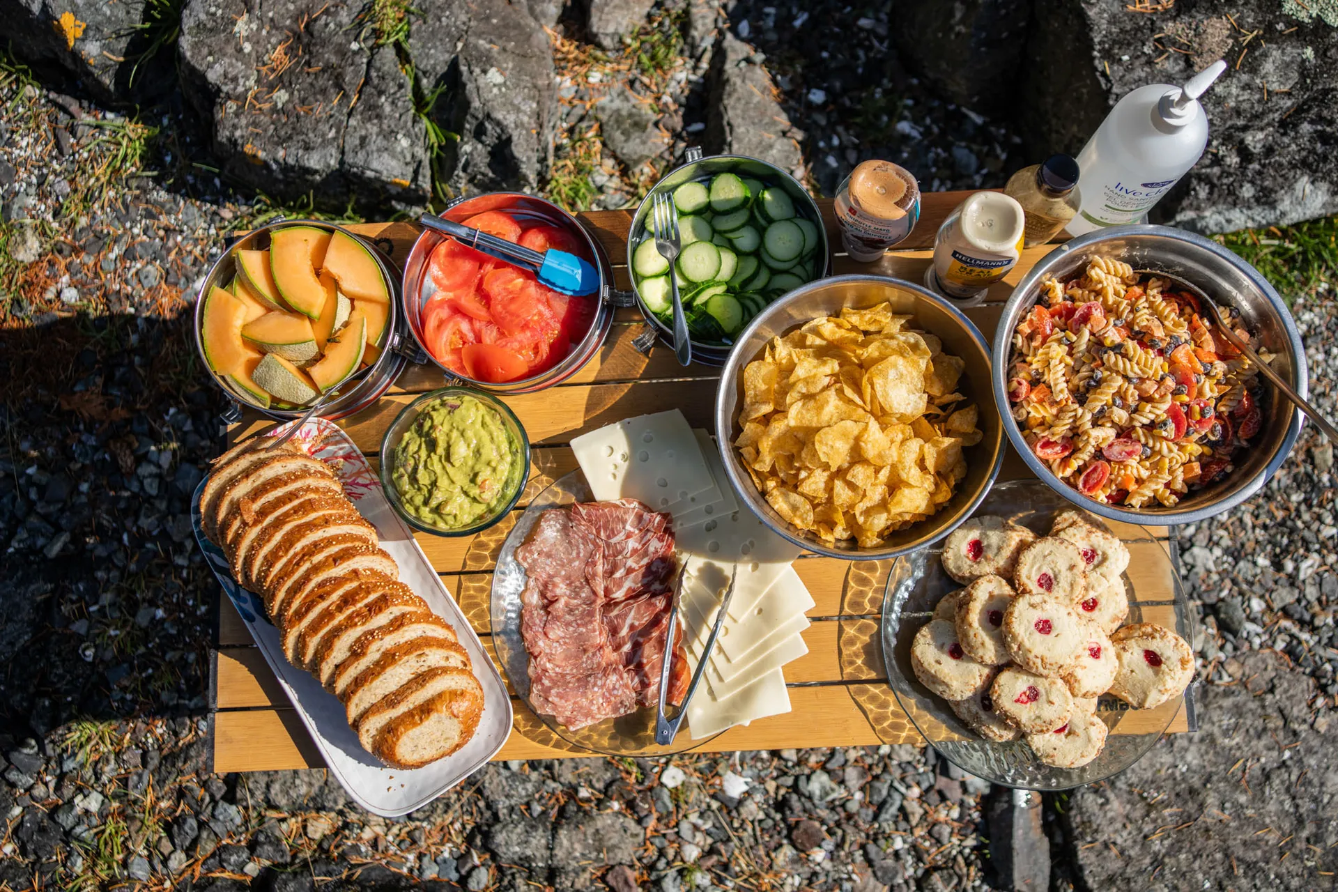 Shore lunch laid out on a folding table — bread, cured meat, salads, fruit and cookies
