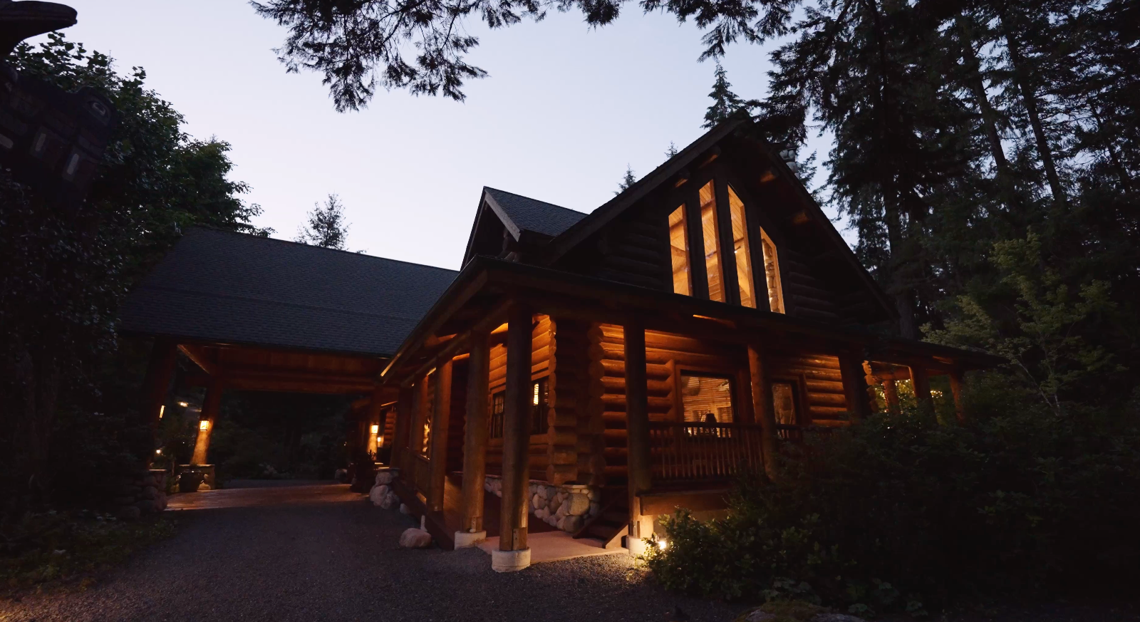 The Lodge at Gold River's timber main building lit warmly at dusk beneath tall conifers